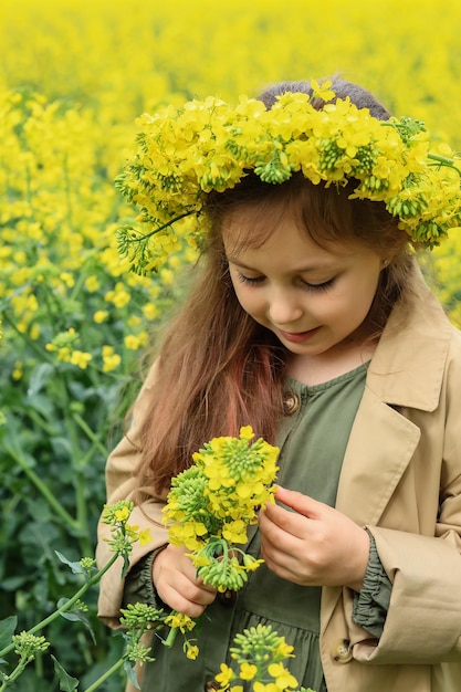 portrait d'une jolie fille de six ans avec une couronne de fleurs de colza sur la tête
