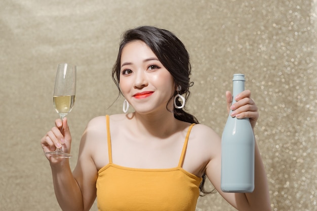 Portrait de jolie fille souriante dans les mains bouteille de champagne et verres à vin avec champagne.