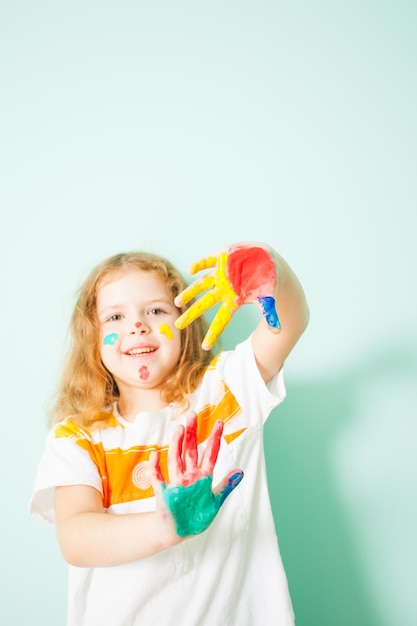 Portrait d'une jolie fille souriante montrant ses paumes peintes à la caméra. Fille créative après sa leçon de peinture