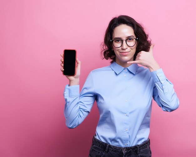 Portrait d&#39;une jolie fille souriante en vêtements d&#39;été à l&#39;aide de téléphone portable en position debout isolée