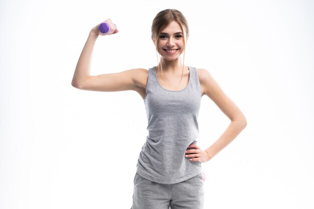 Portrait de jolie fille sportive tenant des haltères de poids et faire des exercices sur blanc.