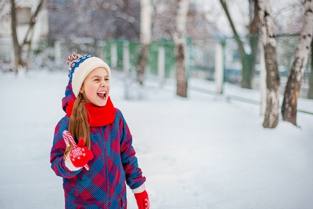 Portrait d'une jolie fille avec sucette de Noël en mains sur une rue d'hiver.