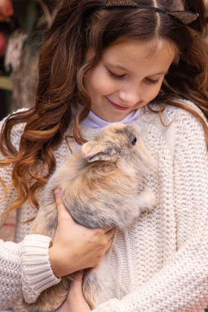 portrait d'une jolie fille tenant un lapin duveteux à l'automne dans la cour