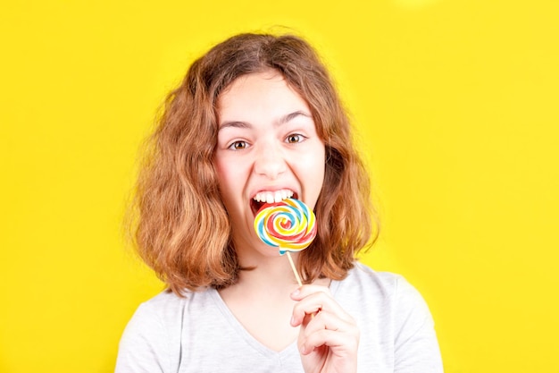 Portrait d'une jolie fille tenant une sucette sur un fond jaune