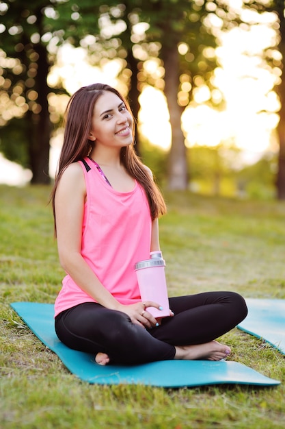 Portrait d&#39;une jolie fille en tenue de sport rose, qui tient une bouteille d&#39;eau ou un cocktail de protéines.