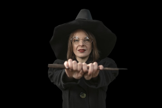 Portrait jolie fille en vêtements de sorcière Femme portant des lunettes chapeau pointu noir et manteau isolé sur fond noir