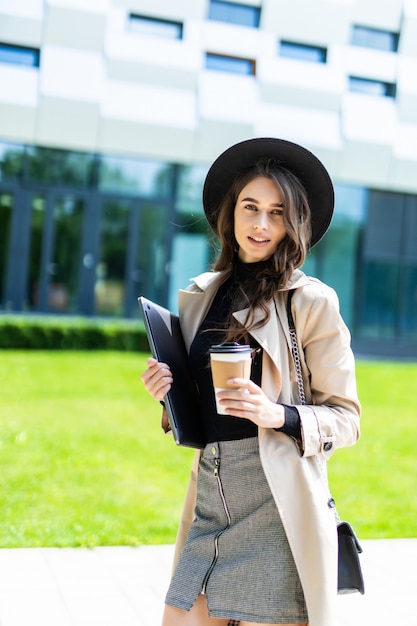 Portrait d'une jolie jeune étudiante sur le campus avec du café à emporter. Étudiante universitaire allant au collège