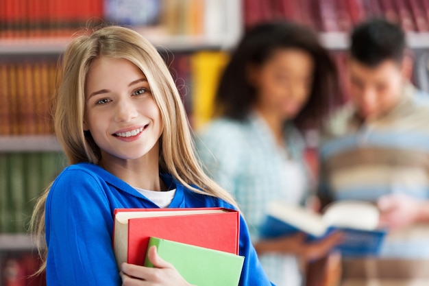 Portrait d'une jolie jeune étudiante tenant des cahiers colorés