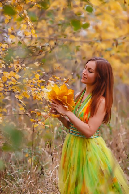 Portrait de jolie jeune femme d'apparence slave en robe de couleur jaune en automne, promenade en forêt. Le modèle mignon se promène dans le parc en automne doré sur fond de nature