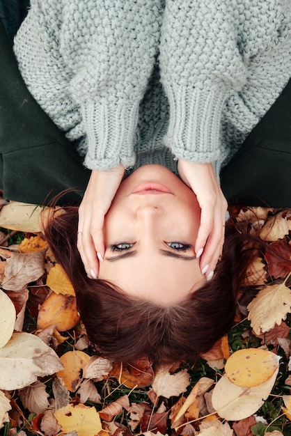 Portrait d'une jolie jeune femme d'apparence slave en tenue décontractée en automne, allongée sur des feuilles jaunes d'automne. Un modèle mignon se promène dans le parc en automne doré sur fond de nature. Espace de copie