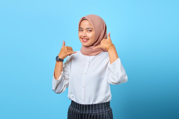 Portrait d'une jolie jeune femme asiatique joyeuse faisant un geste de téléphone avec la main