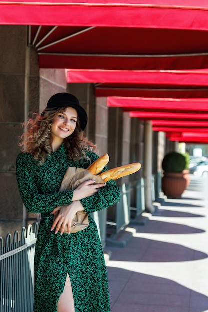 Portrait jolie jeune femme avec baguette dans les mains sur la rue