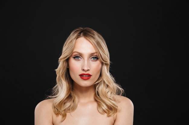 Portrait d'une jolie jeune femme blonde avec des lèvres rouges maquillage lumineux posant isolé.
