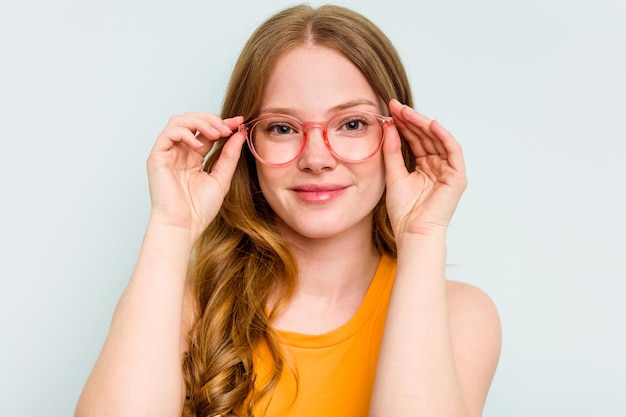 Portrait d'une jolie jeune femme caucasienne portant des lunettes isolée sur fond bleu