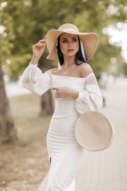 Portrait d'une jolie jeune femme en chapeau et robe en plein air