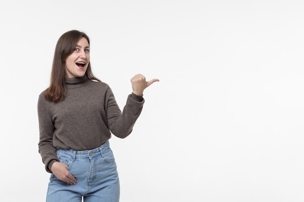 Portrait d'une jolie jeune femme joyeuse ravie et attrayante avec des cheveux raides montrant un espace de copie et un fond blanc isolé