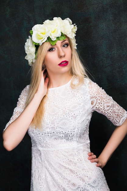 Portrait de jolie jeune femme joyeuse en robe blanche et couronne de fleurs