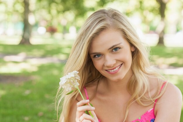 Portrait de jolie jeune femme montrant une fleur blanche