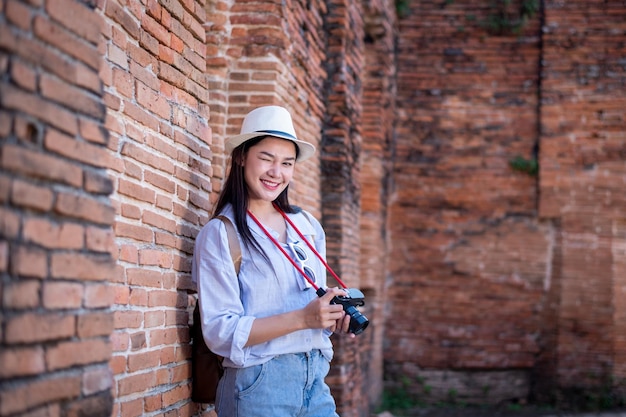 Portrait d'une jolie jeune femme posant portant de belles robes s'amusant et heureuse dans le célèbre ancien palais d'Ayutthaya avec une caméra voyage avec prendre une photo est un concept de voyage vacances détendu
