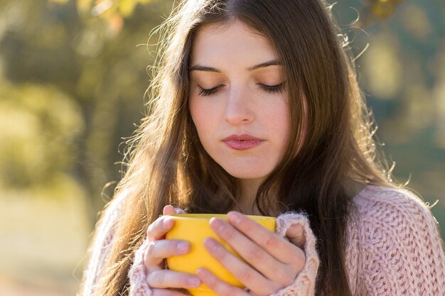 Portrait de jolie jeune femme en pull tricoté élégant debout avec une tasse jaune