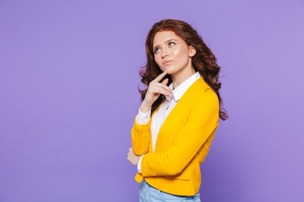 Portrait d'une jolie jeune femme rousse debout sur violet, les bras croisés