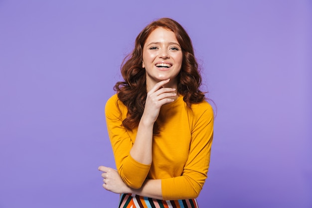 Portrait d'une jolie jeune femme rousse debout sur violet, posant, gesticulant