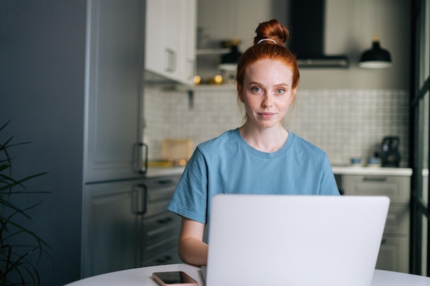 Portrait D'une Jolie Jeune Femme Rousse Travaillant En Tapant Sur Un Ordinateur Portable Assis à Table