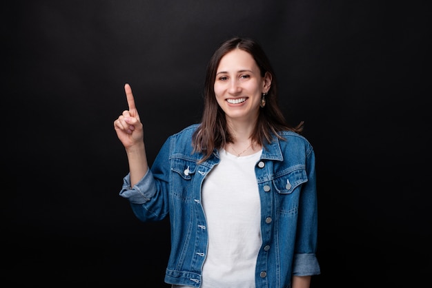 Portrait de jolie jeune femme souriante et pointant loin au fond