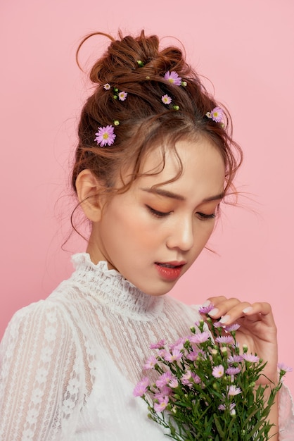 Portrait d'une jolie jeune femme tenant le bouquet et regardant par-dessus son épaule isolé sur rose