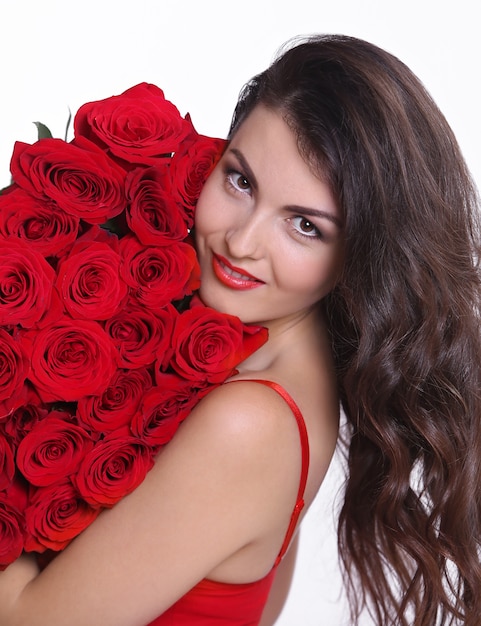 Portrait d'une jolie jeune femme vêtue d'une robe rouge tenant un bouquet de roses isolé sur fond blanc