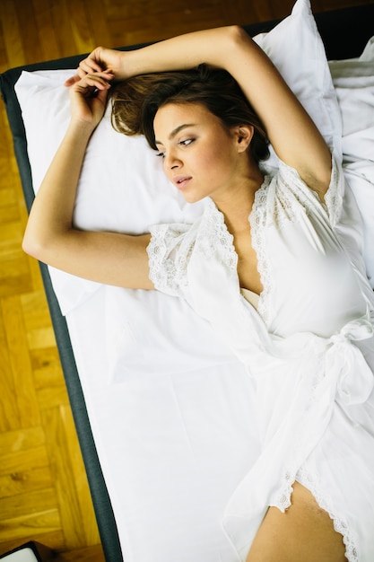 Portrait jolie jeune fille sur le lit dans un appartement moderne le matin