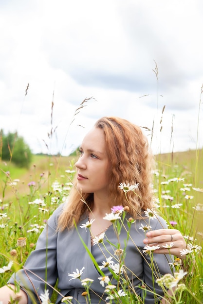 Portrait de jolie jeune fille en robe avec des fleurs sauvages en été