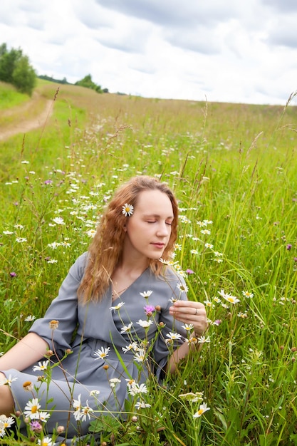 Portrait de jolie jeune fille en robe avec des fleurs sauvages en été