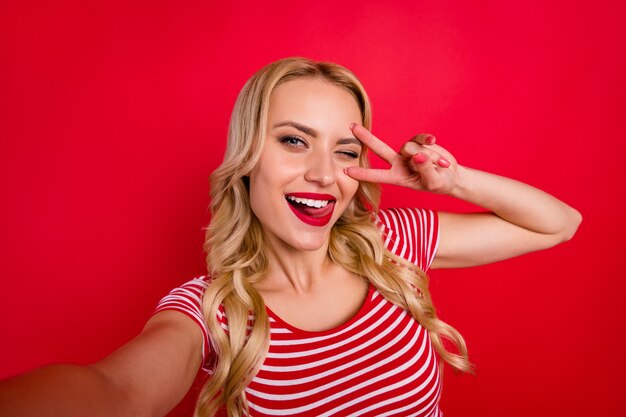 portrait de jolie jolie fille blogueuse faire clignoter les dents de lécher les dents du signe v selfie