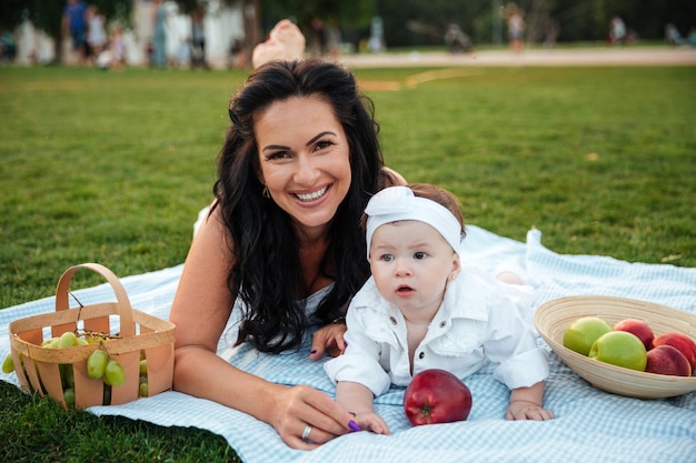 Portrait d'une jolie mère joyeuse et de sa petite fille allongée et relaxante en pique-nique