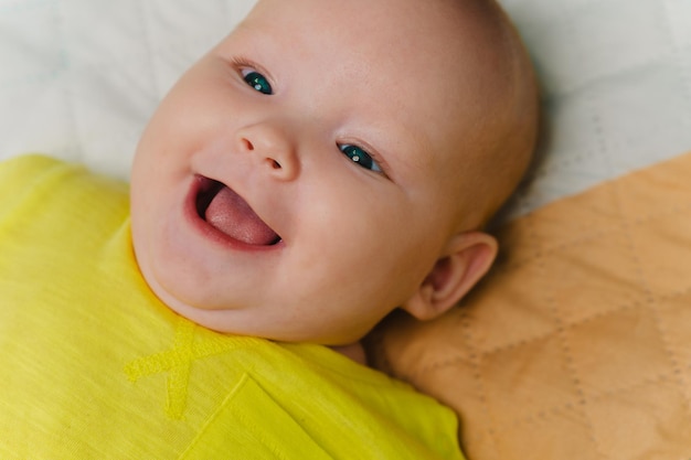 Portrait d'une jolie nouveau-née allongée sur un lit dans un T-shirt jaune