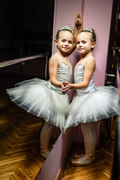 Portrait de jolie petite ballerine touchant le miroir. Jeune danseuse de ballet devant le miroir et sa réflexion. Photographie en noir et blanc.