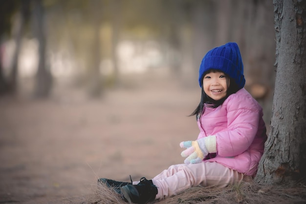 Portrait d'une jolie petite fille asiatique portant des vêtements d'hiver dans la forêt du parcLes gens de Thaïlande posent pour prendre une photoHappy time