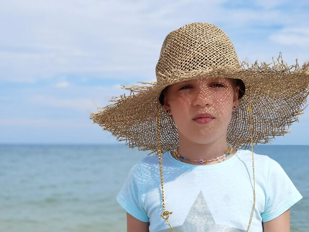 Portrait d'une jolie petite fille au chapeau de paille sur la plage aux beaux jours d'été