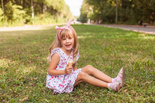 Portrait d'une jolie petite fille blonde avec de la crème glacée lors d'une promenade dans le parc.