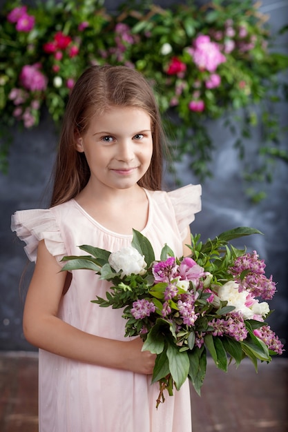 Portrait de la jolie petite fille avec un bouquet de fleurs.