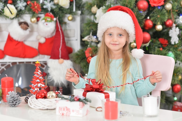 Portrait d'une jolie petite fille avec des cadeaux du Nouvel An dans le chapeau du Père Noël