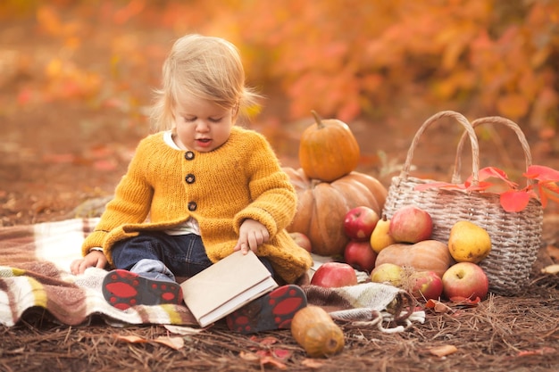 Portrait de jolie petite fille lisant son premier livre au pique-nique dans le parc d'automne