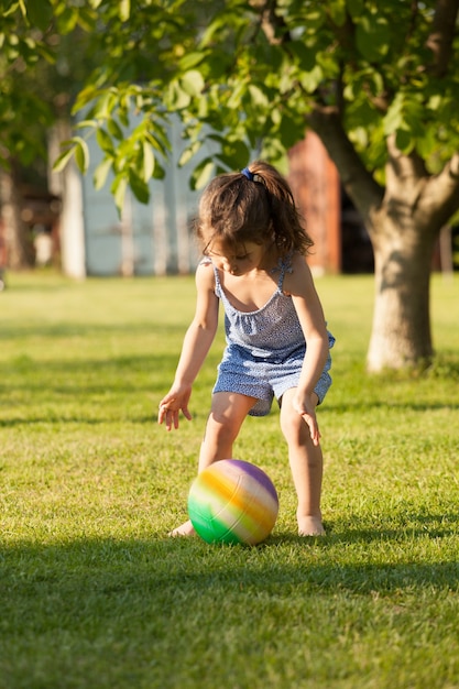 Portrait d'une jolie petite fille qui joue avec le ballon coloré dans la cour rurale