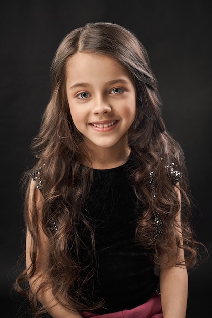 Portrait de jolie petite fille en robe de velours noir.