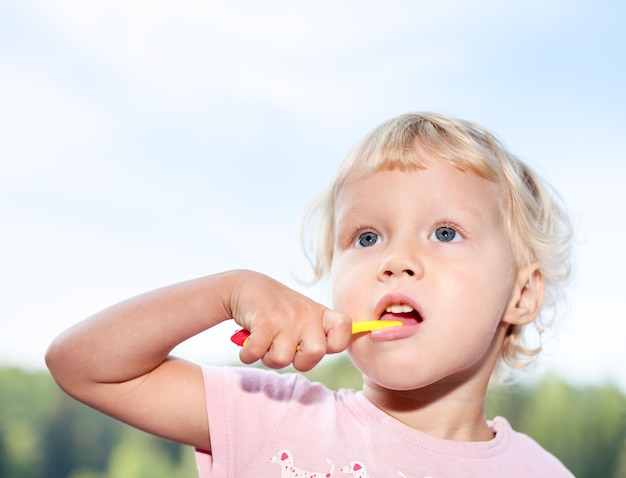 Portrait d'une jolie petite fille se brossant les dents en plein air