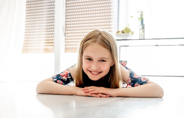 Portrait d'une jolie petite fille souriante allongée sur le sol