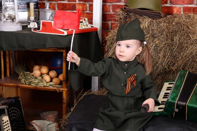 Portrait d'une jolie petite fille en uniforme sur fond rustique Fête de la Victoire le 9 mai