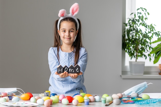 Portrait d'une jolie petite fille vêtue d'oreilles de lapin de Pâques tenant des œufs colorés.