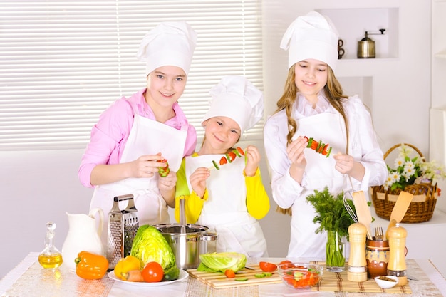 Portrait de jolies filles heureuses cuisinant un plat de légumes